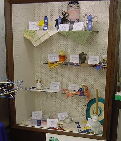 Display case with mugs, cups, and other items with handmade mats