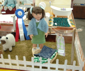 Doll standing near basket and clothesline.